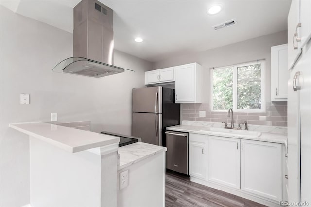 2267 S Buckley Rd Unit 202, Aurora, CO 80013 - kitchen with island exhaust hood, appliances with stainless steel finishes, a peninsula, white cabinetry, and decorative backsplash