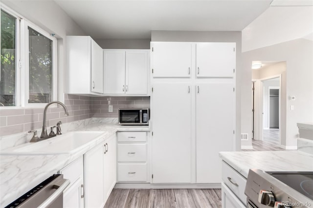 2267 S Buckley Rd Unit 202, Aurora, CO 80013 - kitchen with appliances with stainless steel finishes, white cabinets, light wood-type flooring, light stone counters, and decorative backsplash