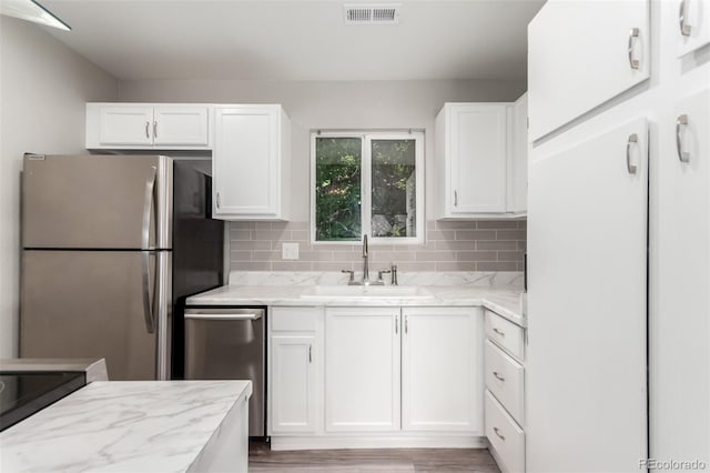 2267 S Buckley Rd Unit 202, Aurora, CO 80013 - kitchen with appliances with stainless steel finishes, white cabinets, light stone countertops, and decorative backsplash