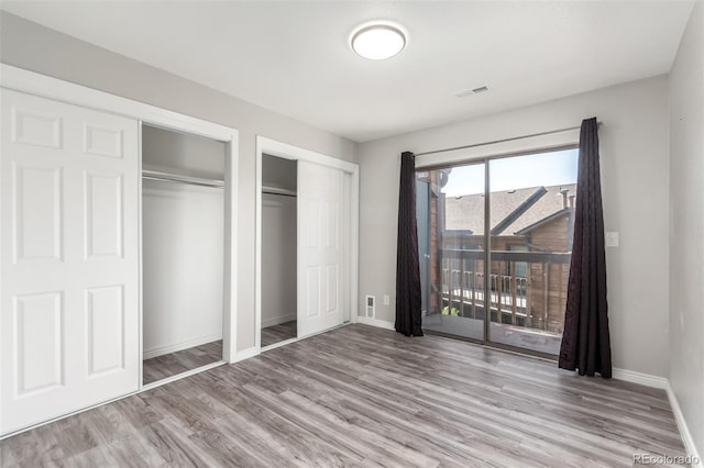 2267 S Buckley Rd Unit 202, Aurora, CO 80013 - unfurnished bedroom with two closets, wood finished floors, and access to outside