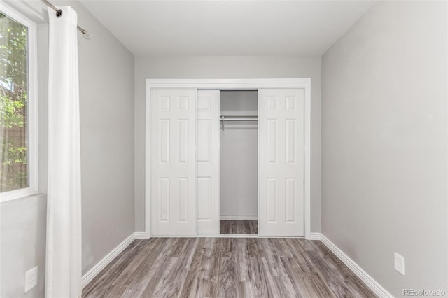 2267 S Buckley Rd Unit 202, Aurora, CO 80013 - unfurnished bedroom featuring wood finished floors, multiple windows, and a closet