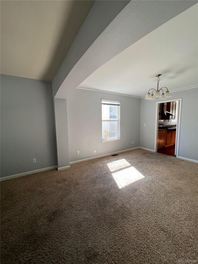 carpeted empty room with baseboards, an inviting chandelier, and ornamental molding