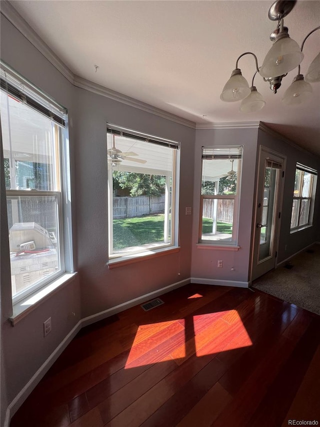 unfurnished dining area with visible vents, wood-type flooring, ornamental molding, and baseboards