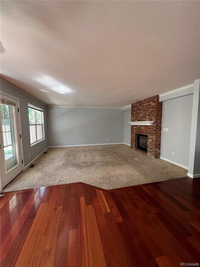 unfurnished living room featuring wood-type flooring, a textured ceiling, a brick fireplace, and vaulted ceiling