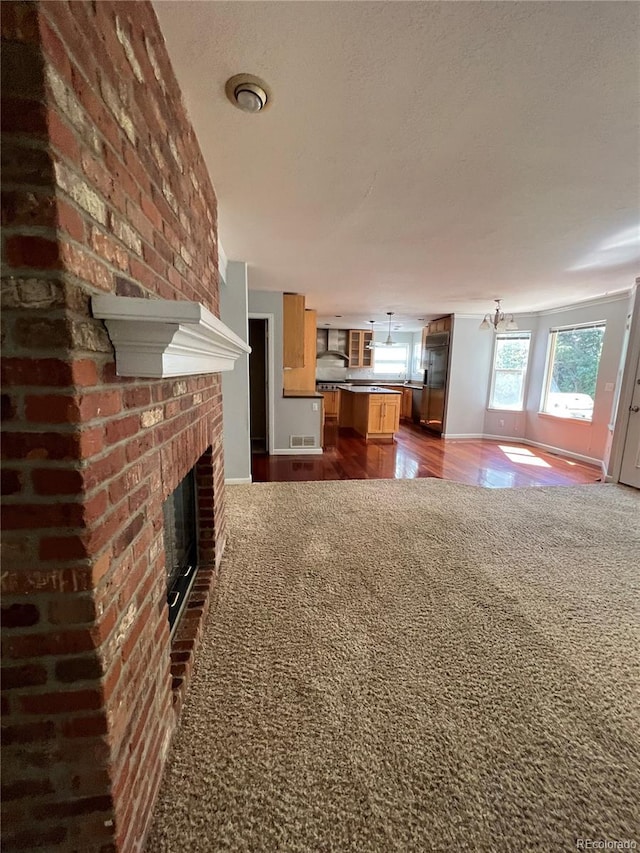 unfurnished living room with dark wood finished floors, baseboards, a textured ceiling, and a fireplace