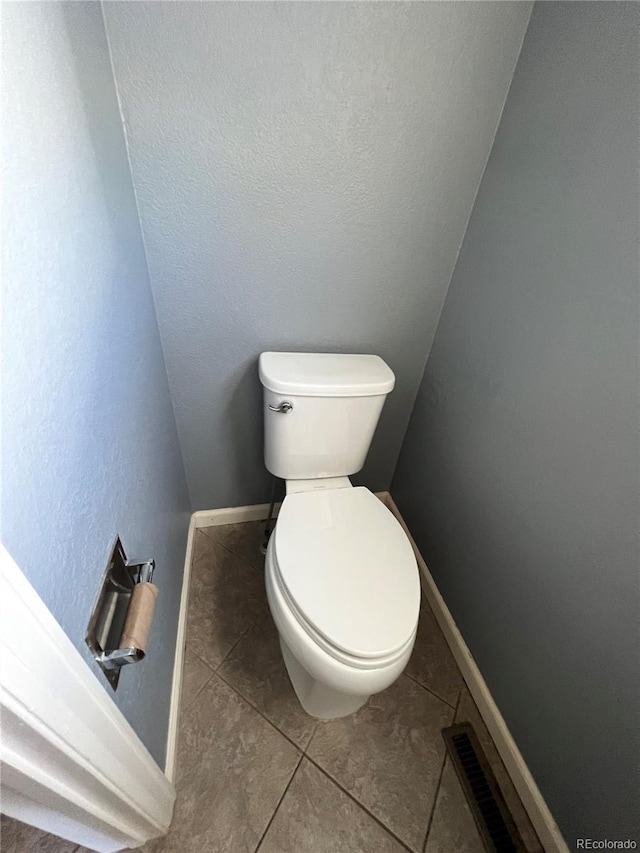 bathroom featuring toilet, tile patterned floors, baseboards, and visible vents
