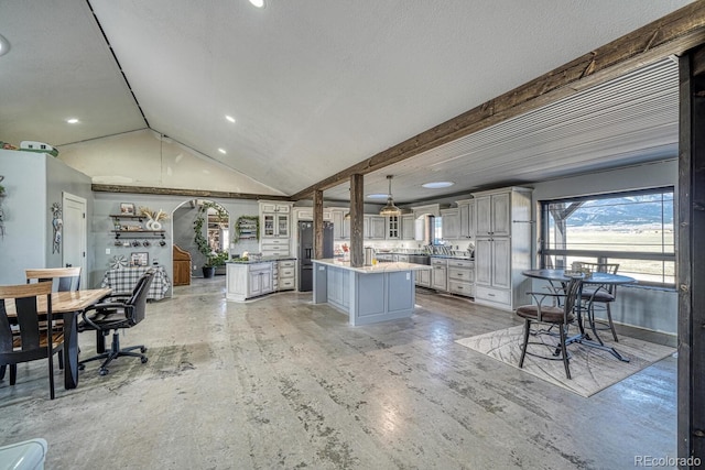 kitchen featuring refrigerator with ice dispenser, a center island, glass insert cabinets, lofted ceiling, and decorative light fixtures