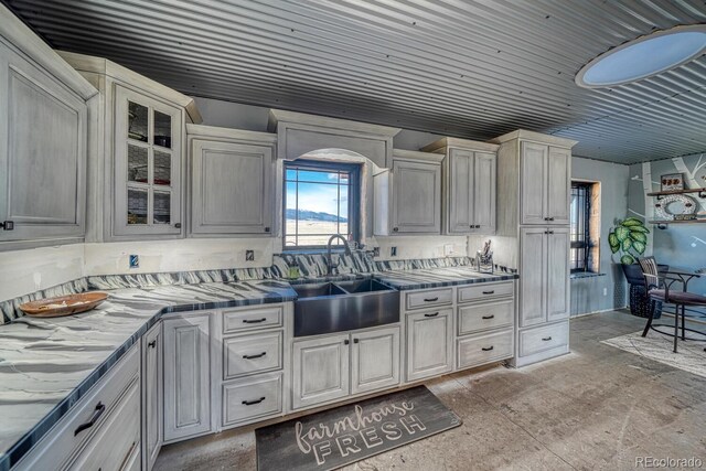kitchen featuring a sink, arched walkways, and glass insert cabinets