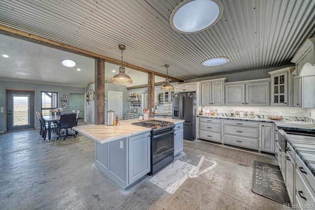 kitchen featuring concrete floors, stainless steel fridge, a center island, glass insert cabinets, and range with gas stovetop
