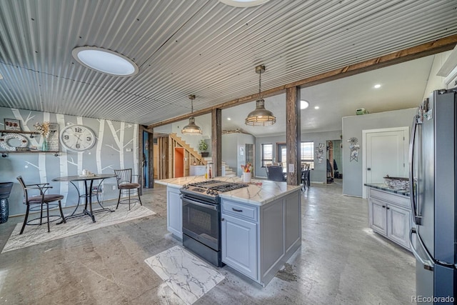 kitchen with a center island, range with gas cooktop, hanging light fixtures, freestanding refrigerator, and light stone countertops