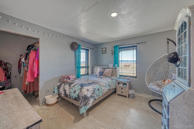 bedroom with baseboards, a closet, a spacious closet, and a textured ceiling