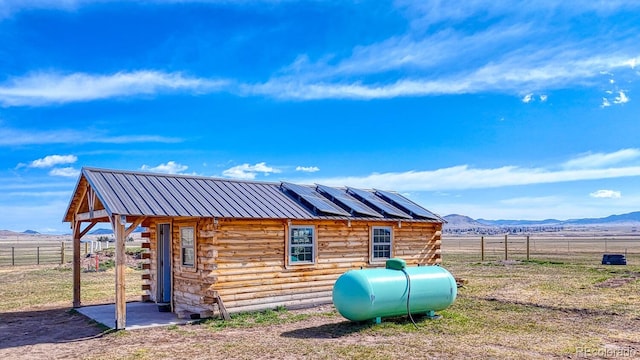view of outdoor structure featuring solar panels, a mountain view, and fence