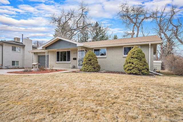 ranch-style home featuring a front yard, brick siding, roof with shingles, and an attached garage