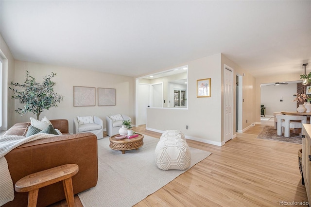 living room with light wood-style flooring, baseboards, and ceiling fan