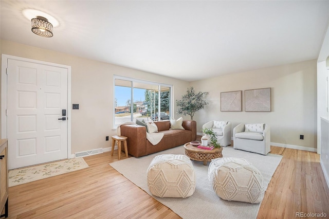 living room featuring visible vents, baseboards, and light wood-style floors