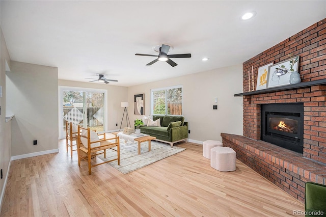 living area featuring a wealth of natural light, a fireplace, ceiling fan, and wood finished floors