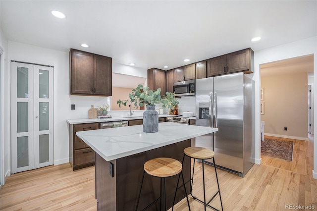 kitchen with dark brown cabinetry, appliances with stainless steel finishes, and light wood-type flooring