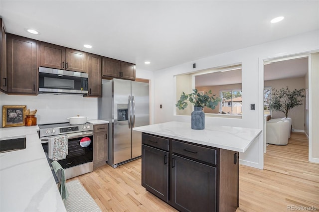 kitchen with light stone counters, recessed lighting, appliances with stainless steel finishes, light wood finished floors, and dark brown cabinets