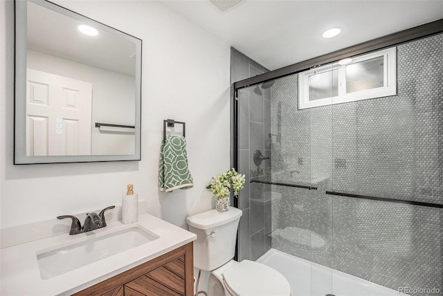 full bathroom featuring vanity, a shower stall, toilet, and visible vents