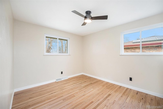 spare room featuring light wood-type flooring, visible vents, and a healthy amount of sunlight