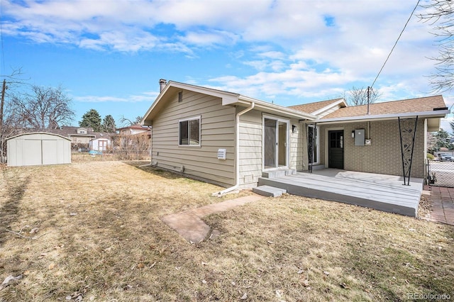 back of property with a yard, an outbuilding, fence, and a shed