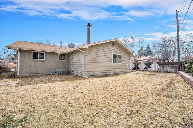 rear view of house with fence, brick siding, and central AC