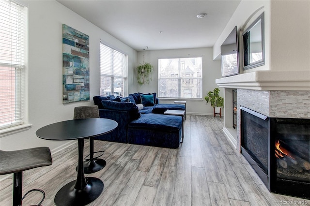 living room featuring a stone fireplace and light wood-type flooring