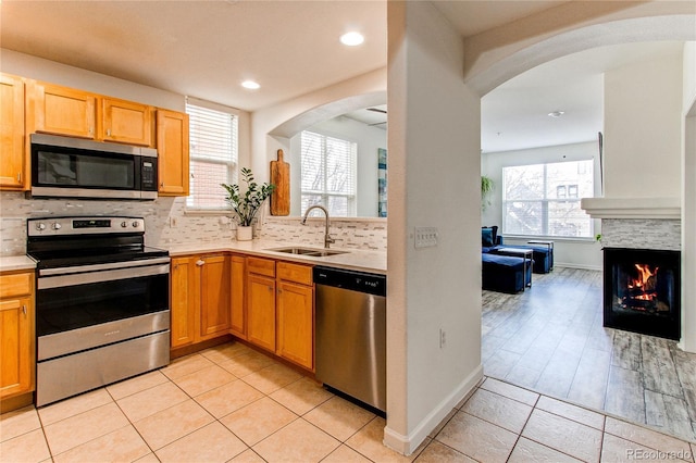 kitchen with a healthy amount of sunlight, appliances with stainless steel finishes, sink, and a multi sided fireplace