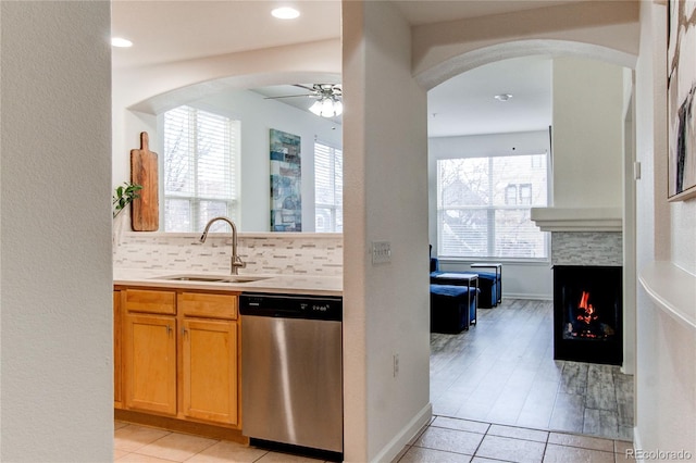 kitchen with tasteful backsplash, sink, stainless steel dishwasher, light tile patterned floors, and ceiling fan