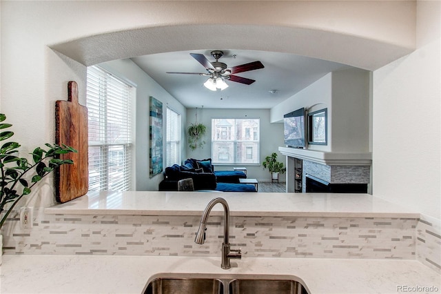 kitchen featuring light stone counters, sink, and ceiling fan