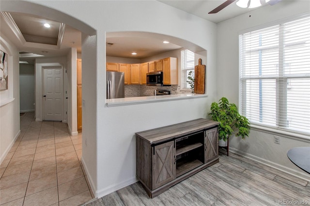 kitchen featuring stainless steel refrigerator, light brown cabinetry, decorative backsplash, and a wealth of natural light