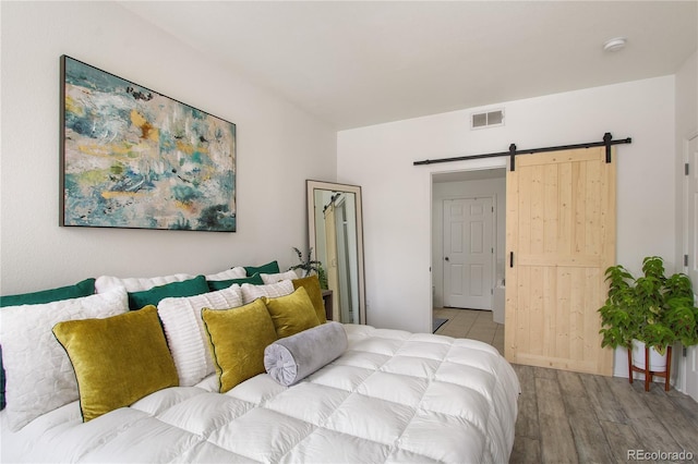 bedroom featuring a barn door and light wood-type flooring