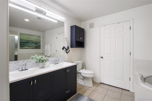 bathroom featuring tile patterned flooring, vanity, tiled bath, and toilet