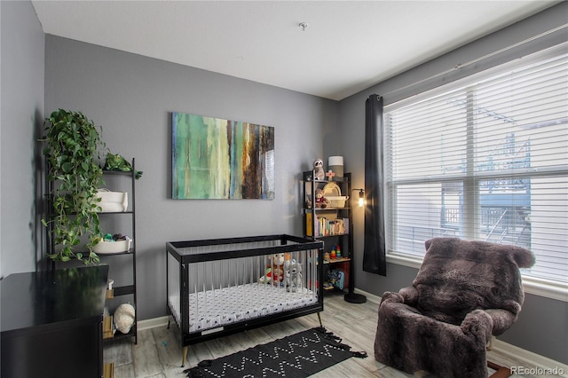 bedroom featuring a nursery area, hardwood / wood-style floors, and multiple windows