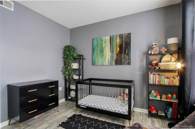 bedroom featuring light hardwood / wood-style flooring and a crib