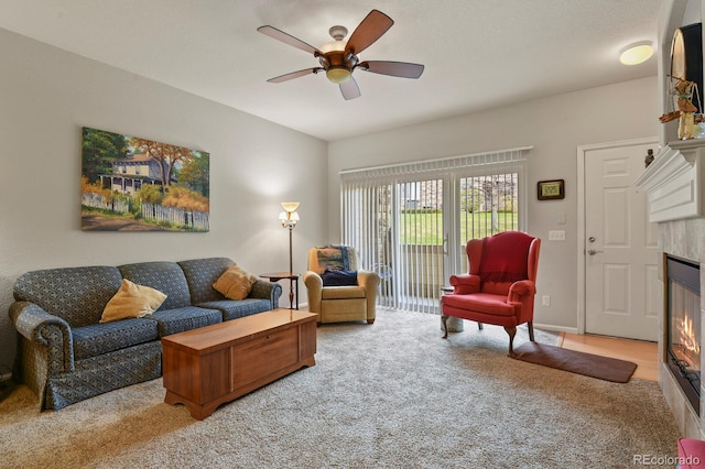 living room featuring ceiling fan, a fireplace, and carpet flooring