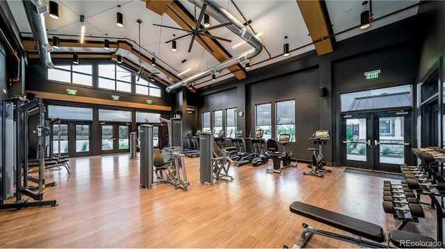 gym featuring hardwood / wood-style floors, a towering ceiling, and french doors