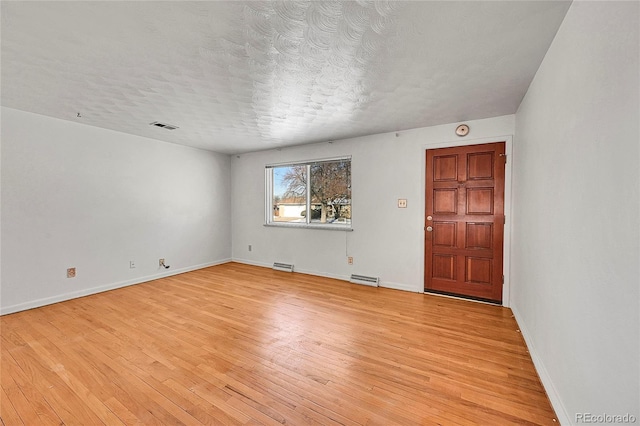 spare room featuring a textured ceiling and light wood-type flooring