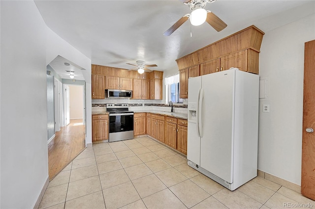 kitchen with light tile patterned flooring, sink, ceiling fan, stainless steel appliances, and backsplash