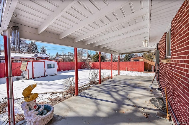 snow covered patio with a storage shed