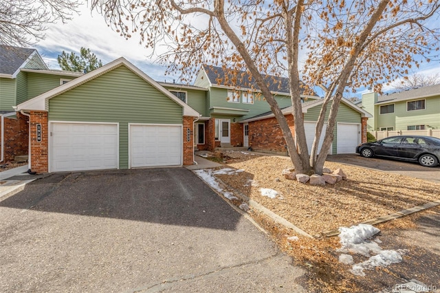 view of front of property featuring a garage, brick siding, and driveway