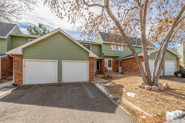 view of front of property featuring brick siding, an attached garage, and driveway