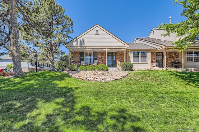 9925 W Progress Pl, Littleton, CO 80123 - view of front of house featuring a front lawn, brick siding, and covered porch