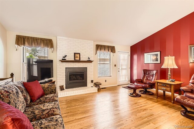 9925 W Progress Pl, Littleton, CO 80123 - living room with wood finished floors, a brick fireplace, an accent wall, baseboards, and lofted ceiling