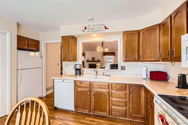 9925 W Progress Pl, Littleton, CO 80123 - kitchen featuring white appliances, a sink, brown cabinetry, light countertops, and wood finished floors