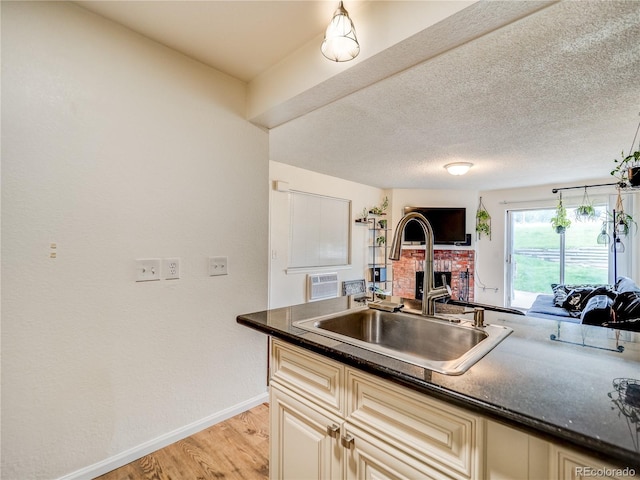 14590 E 2nd Ave Unit 105B, Aurora, CO 80011 - kitchen with a fireplace, cream cabinets, dark countertops, light wood finished floors, and a textured ceiling