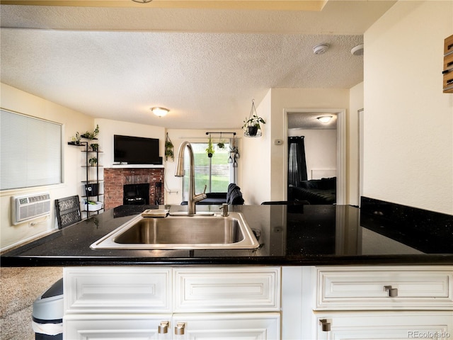 14590 E 2nd Ave Unit 105B, Aurora, CO 80011 - kitchen featuring open floor plan, a wall mounted air conditioner, white cabinetry, a brick fireplace, and a textured ceiling