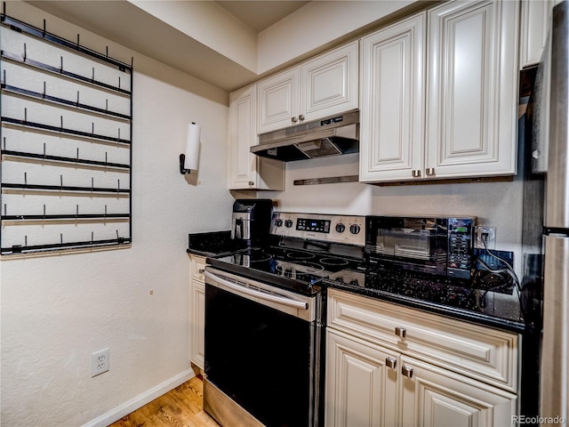14590 E 2nd Ave Unit 105B, Aurora, CO 80011 - kitchen with stainless steel electric range oven, under cabinet range hood, light wood-style floors, freestanding refrigerator, and dark stone countertops