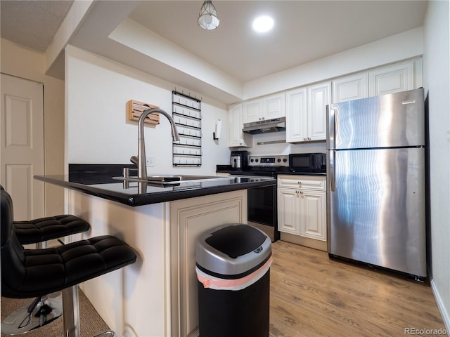 14590 E 2nd Ave Unit 105B, Aurora, CO 80011 - kitchen featuring appliances with stainless steel finishes, under cabinet range hood, a kitchen bar, a peninsula, and dark countertops