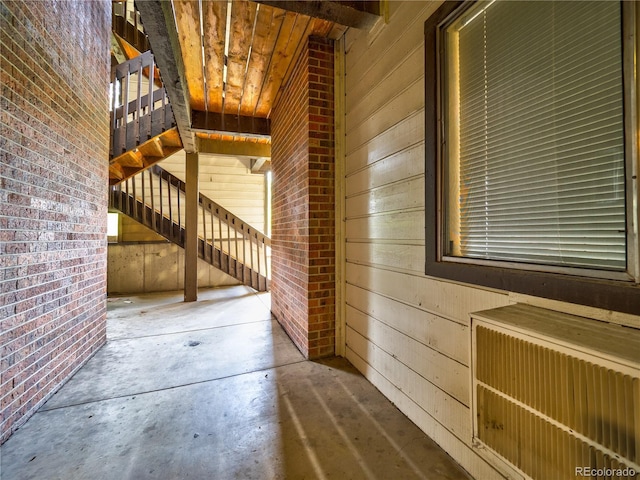 14590 E 2nd Ave Unit 105B, Aurora, CO 80011 - corridor featuring radiator heating unit, brick wall, concrete flooring, and wood walls
